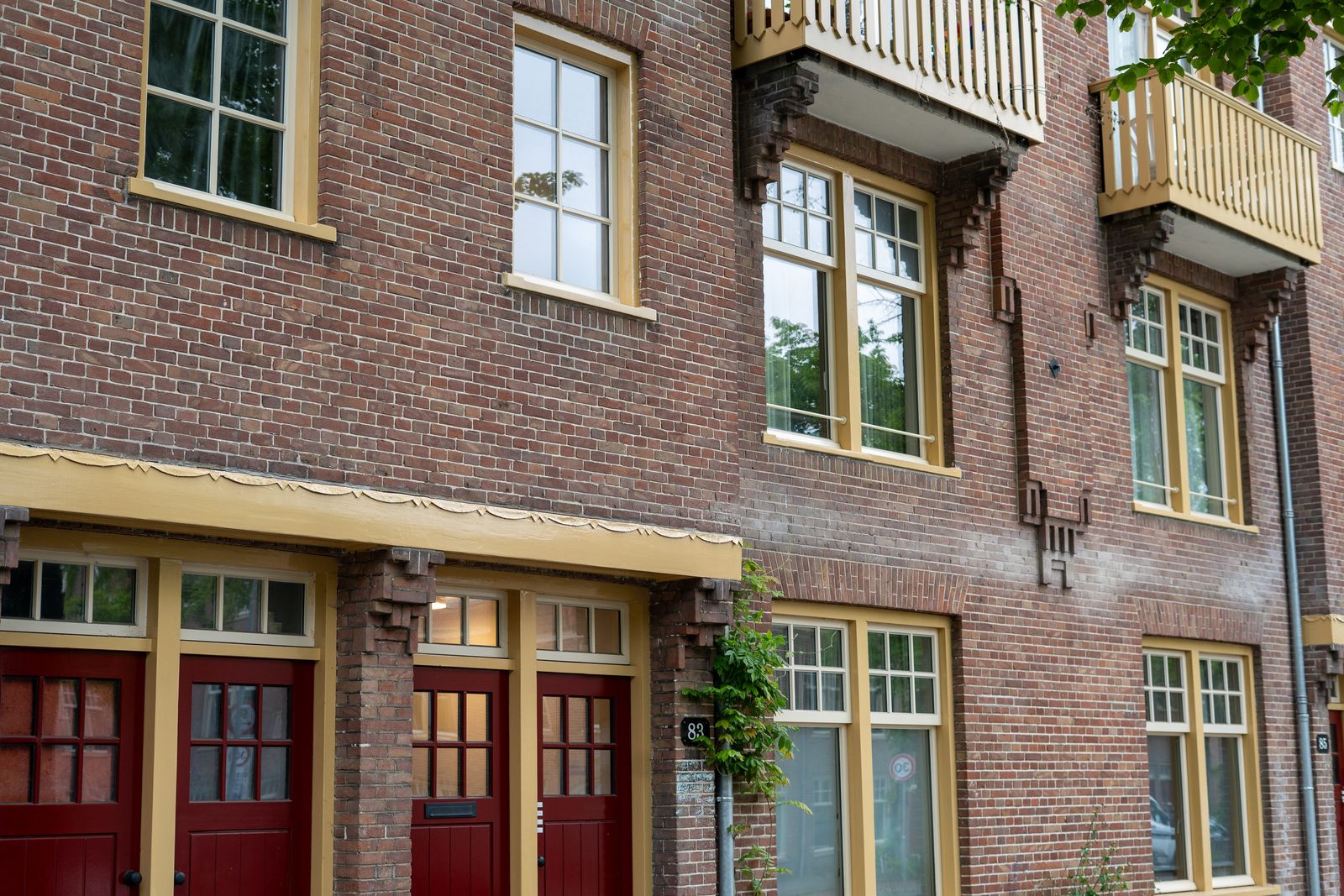 Rode deuren en okergele kozijnen over de volle breedte van het blok