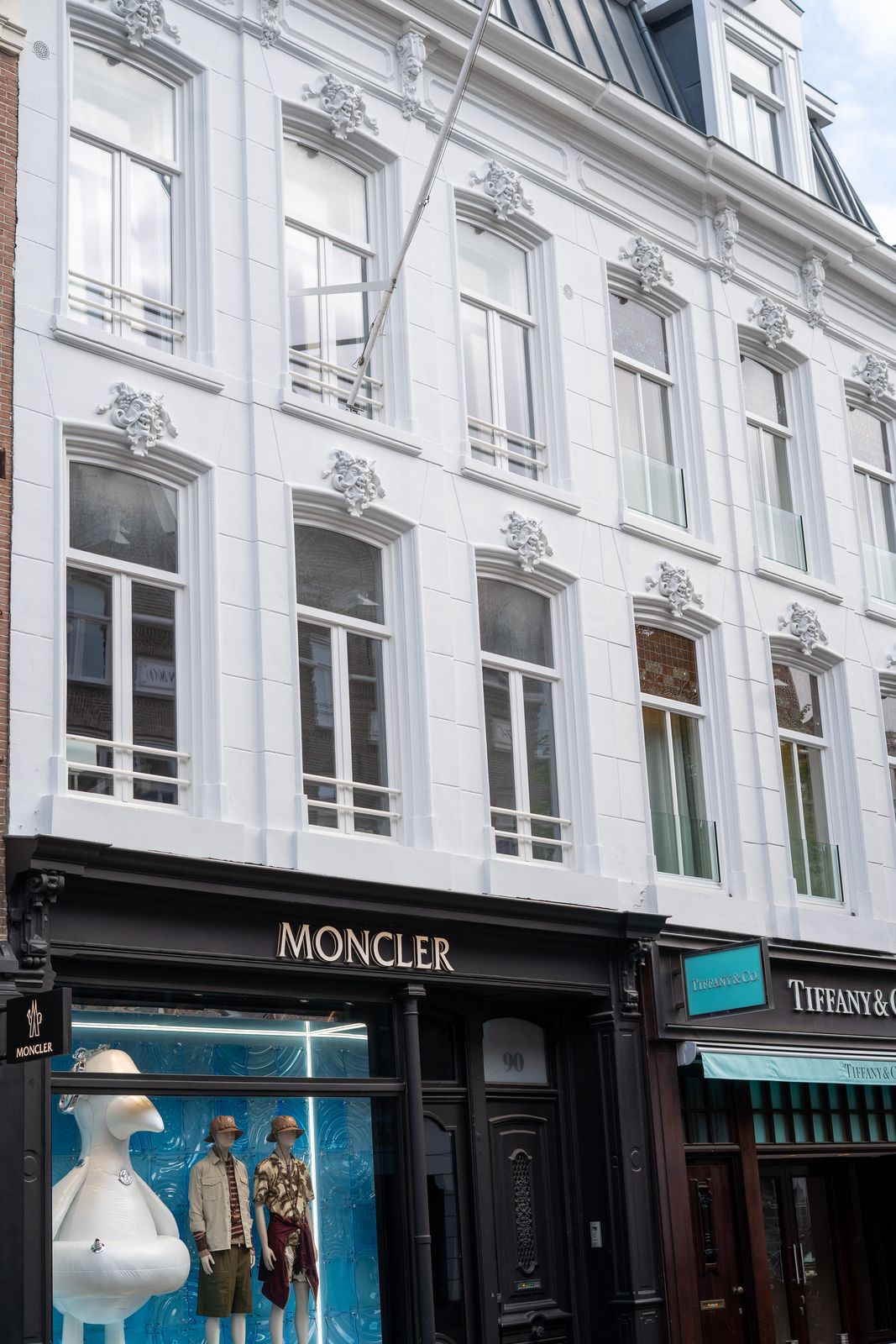 Witte monumentale gevel boven de winkelpuien van Moncler en Tiffany aan de P.C. Hooftstraat